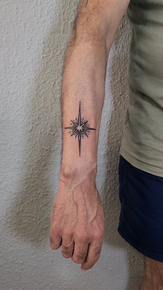 Tatuaje de brújula estelar de líneas finas sobre el antebrazo