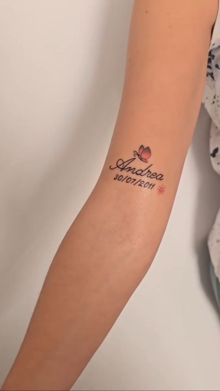 Tatuaje delicado de nombre y fecha con detalles de color